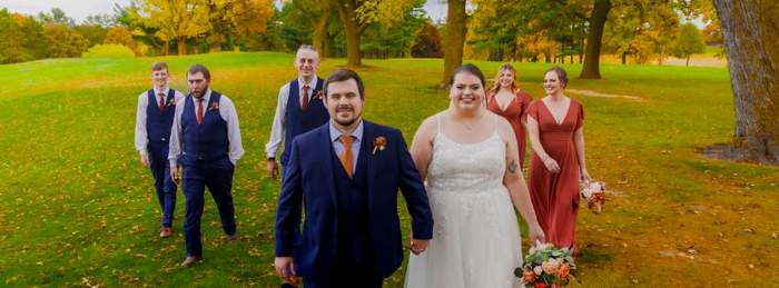 Wedding party walking across a fall lawn