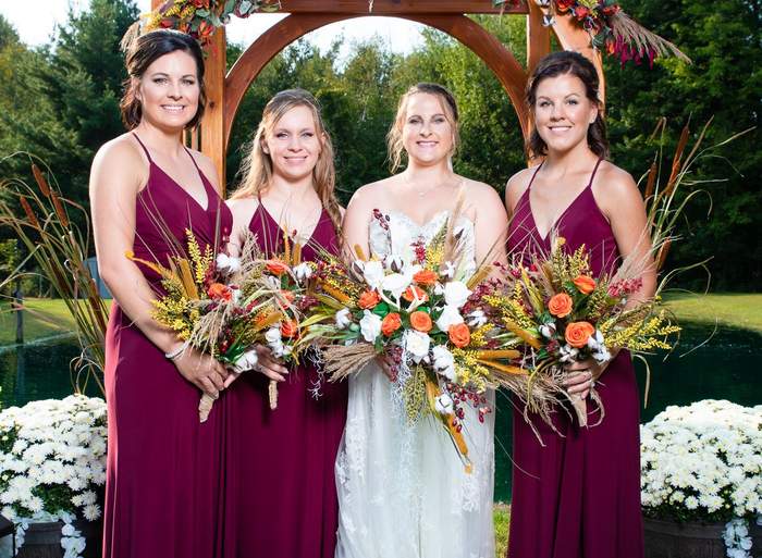 Bride with her bridesmaids under a floral arch