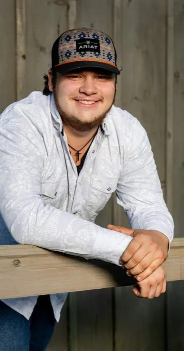 Senior portrait leaning on a fence rail, warm smile