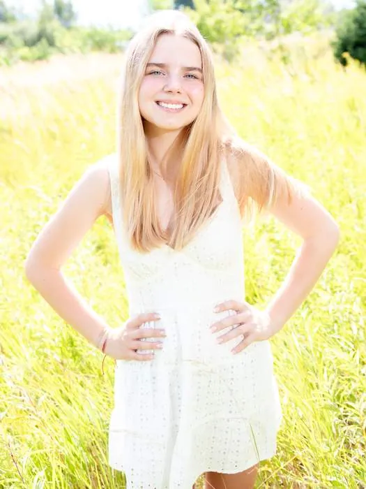 Senior portrait in a white dress in an open field