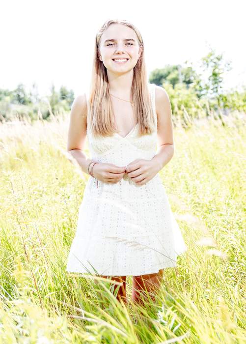Senior portrait smiling in a sunlit field