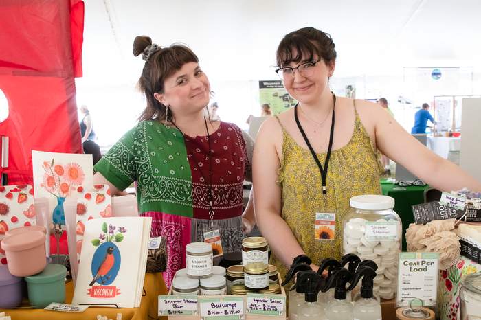 Two vendors at their craft booth, candles and cards on display