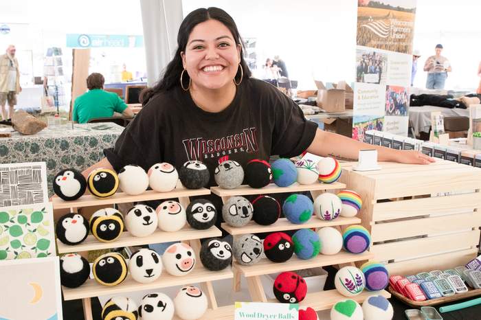 Vendor with a display of handmade wool dryer balls at a fair booth