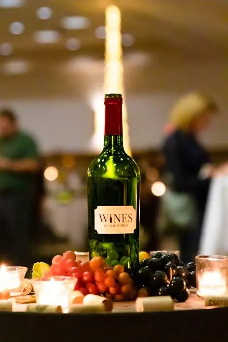 Wine bottle centerpiece with grapes and candlelight at a reception