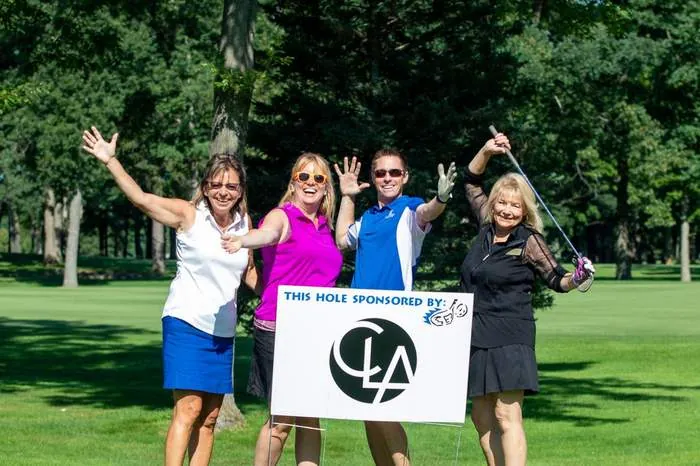 Golf outing foursome celebrating at the sponsor sign