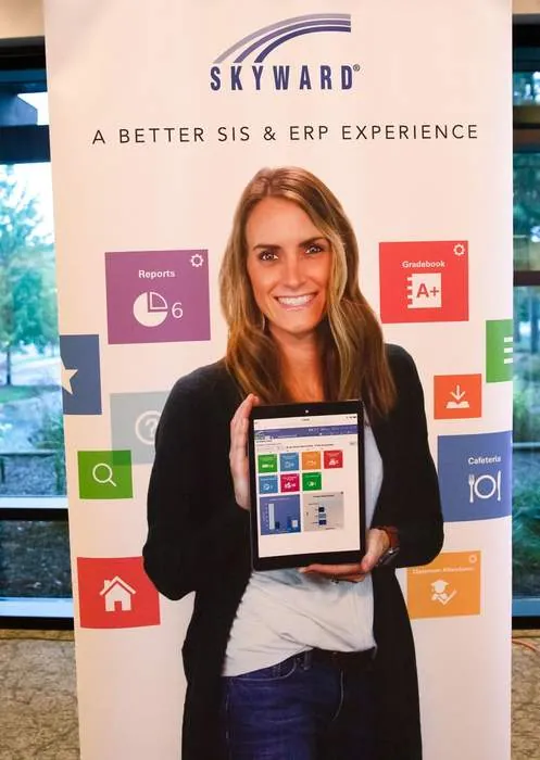 Vendor holding a tablet in front of a trade-show banner