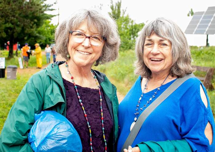 Two friends smiling outdoors at a community energy fair