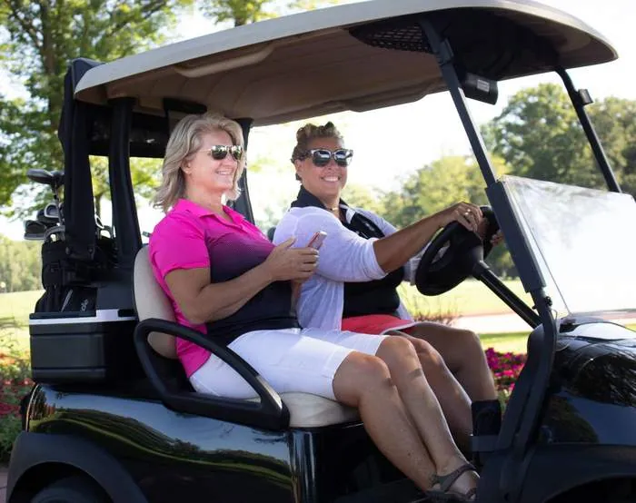 Two golfers riding together and smiling for the camera