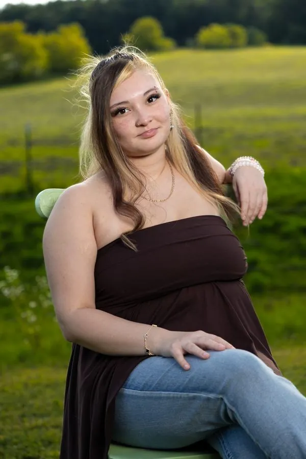Senior portrait leaning on a farm gate