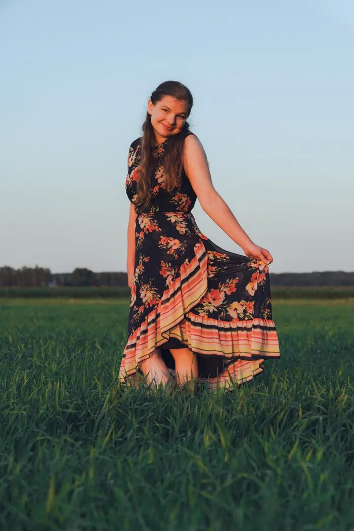 Senior portrait twirling her dress in an open field at golden hour