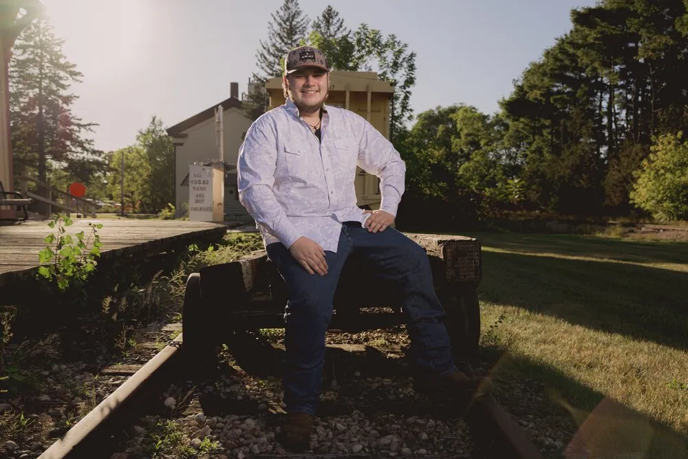Senior portrait seated on a vintage rail car at golden hour