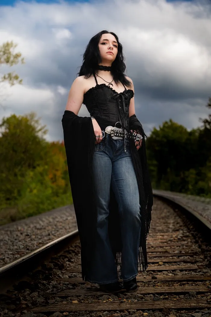 Senior portrait in a dramatic black outfit on railroad tracks