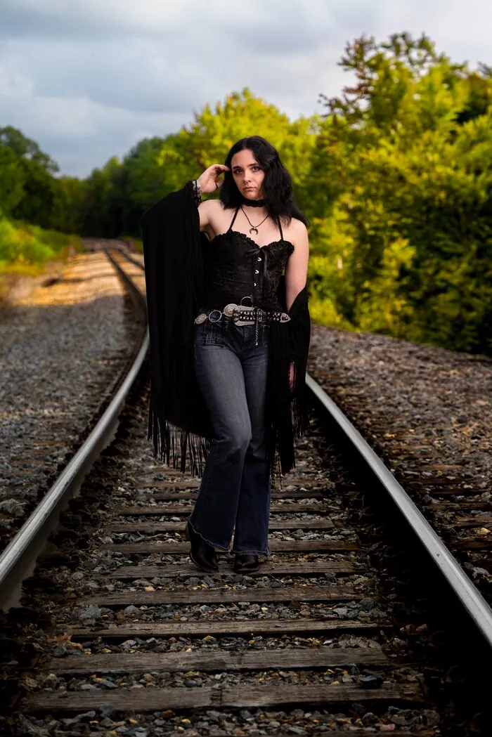 Senior portrait walking the railroad tracks in a black outfit