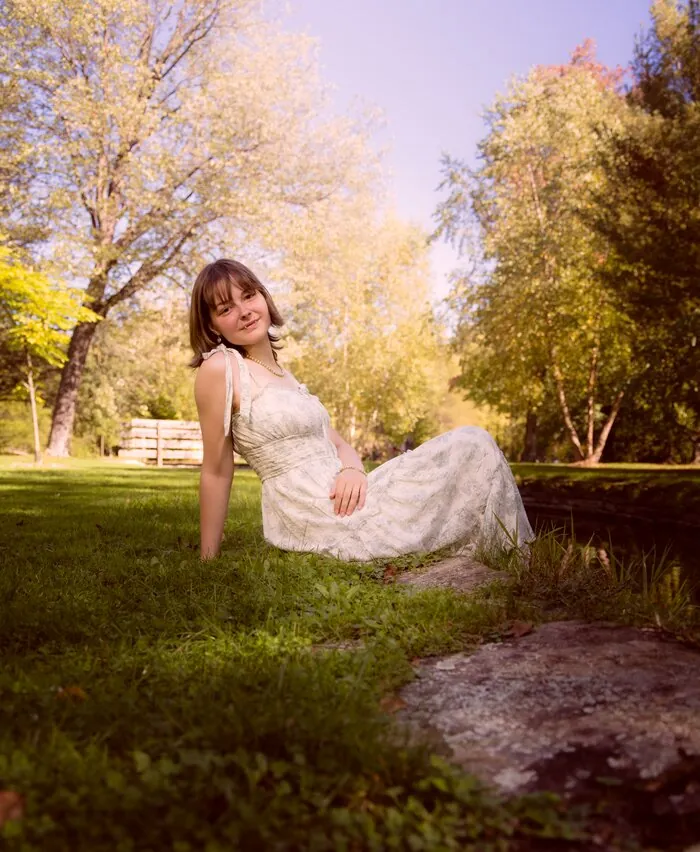 Senior portrait seated by a pond in golden light