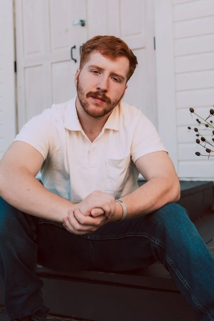 Senior portrait seated on porch steps, hands clasped