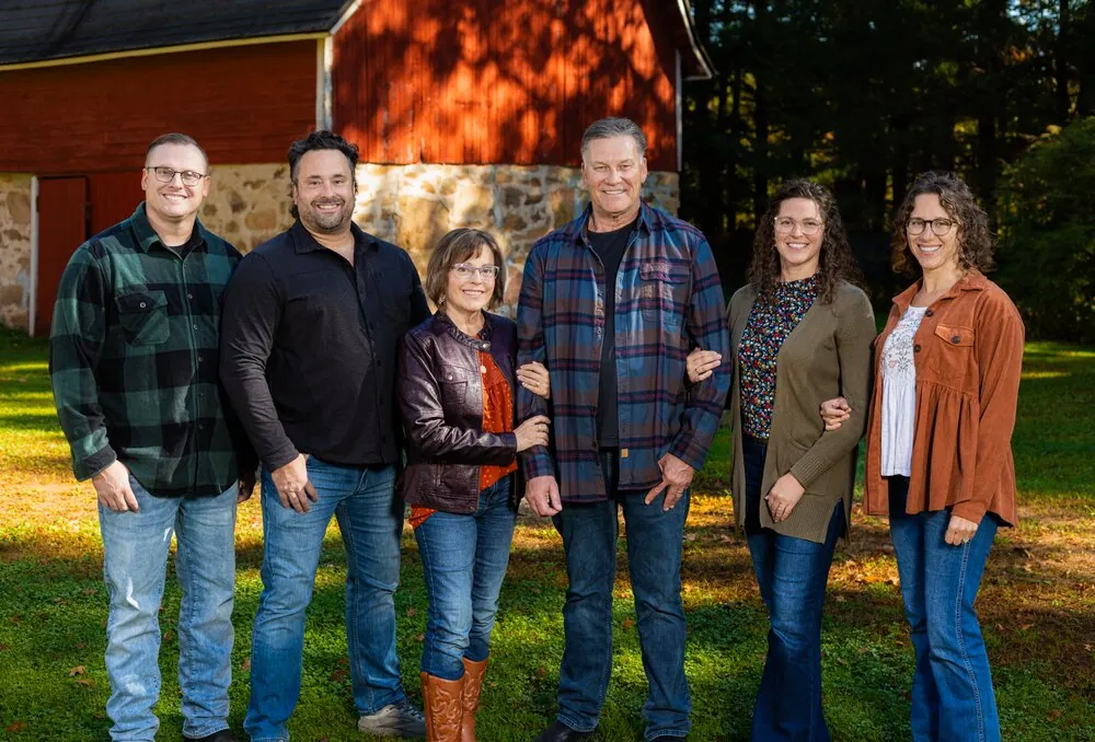 Extended family portrait outdoors by a red barn